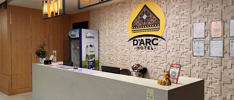 Bancada de recepção no Hotel D'ARC com design moderno, um logotipo fixado e uma parede com certificados.