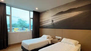 Een hotelkamer met twee bedden, een groot raam en een muurschildering van een berglandschap.