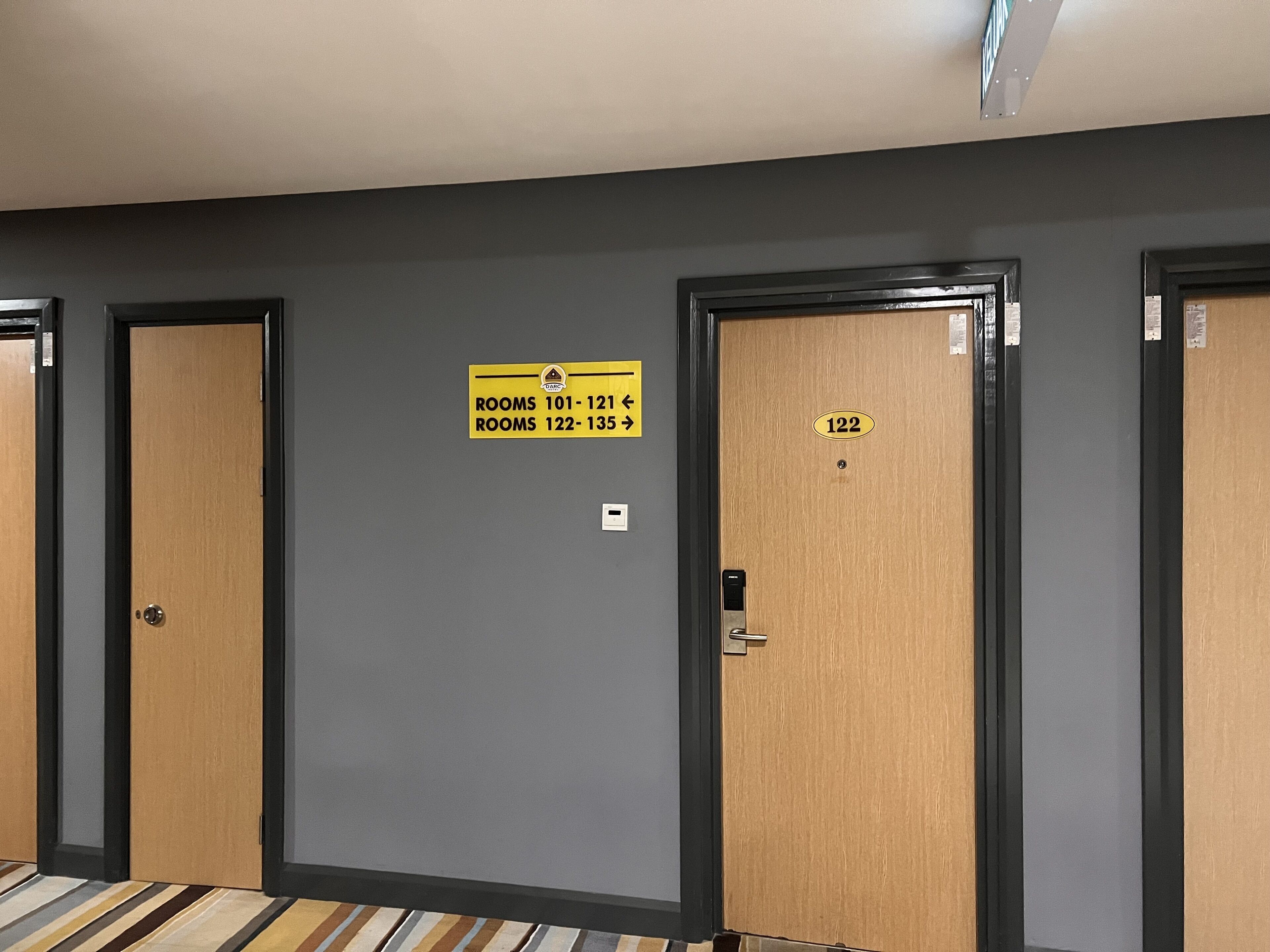 Un couloir avec des portes numérotées de 101 à 121 et de 122 à 135, indiquant les numéros des chambres.