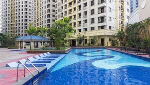 A swimming pool with a blue mosaic design, surrounded by a landscaped area with palm trees and a small pavilion. - Forbeswood Heights near St Lukes (Taguig)