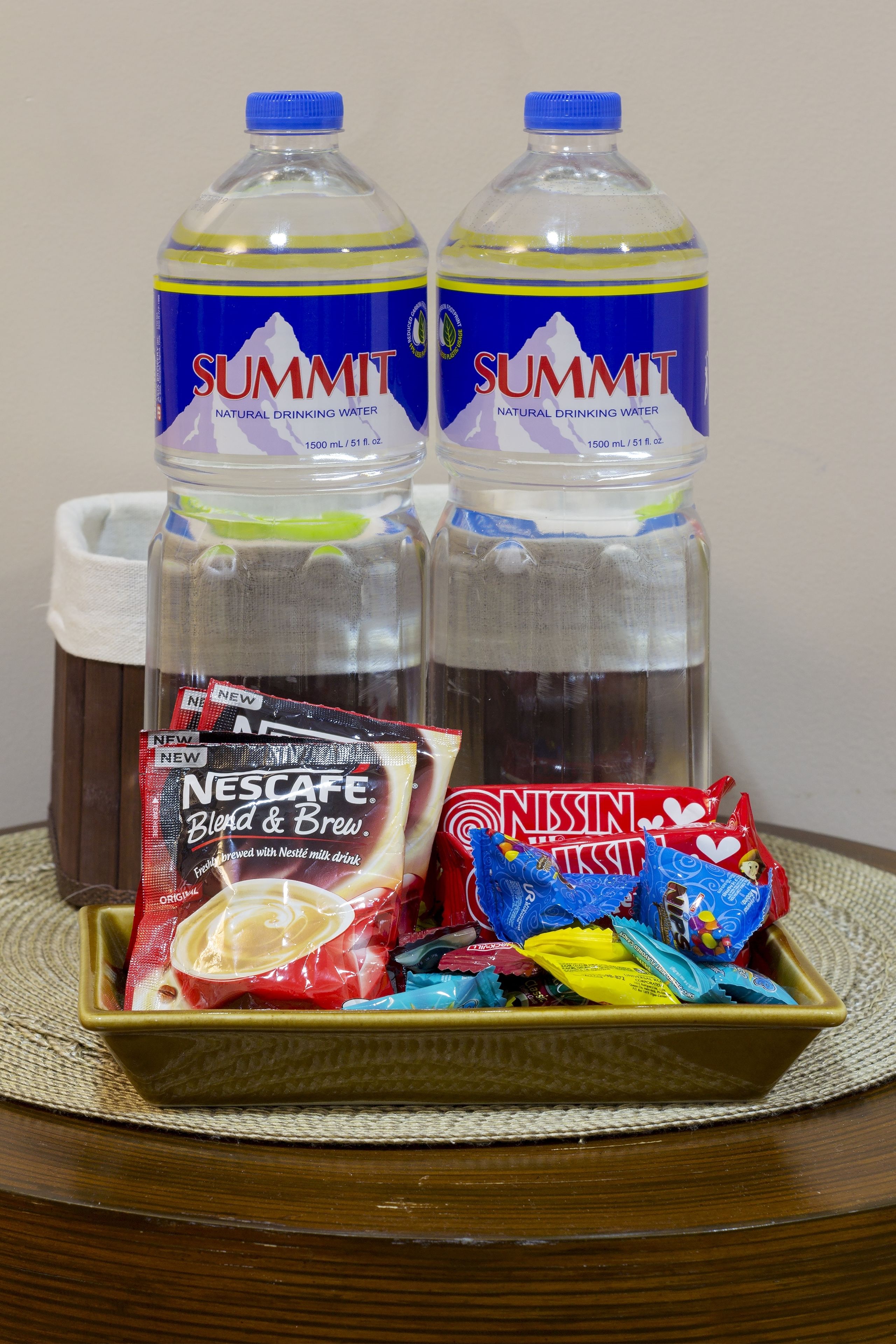 Dos botellas de agua Summit, un paquete de café Nescafé Blend & Brew y un paquete de fideos instantáneos Nissin sobre una bandeja.