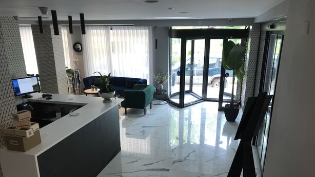 Een moderne woonkamer met een marmeren vloer, een bank, een bijzettafeltje en een groot raam met gordijnen.