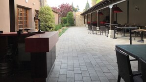 Een terras met betegelde vloer, een bar en zitplaatsen buiten.