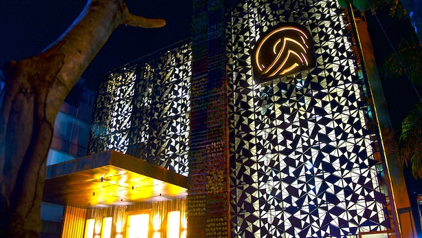 A building with a geometric facade and a prominent illuminated logo. - Rangers Hotel (Devikolam)