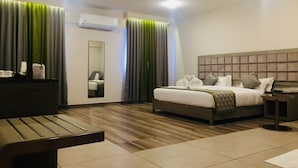 A hotel room with a bed, bedside table, and a bench. - Rangers Hotel (Devikolam)