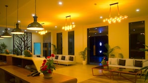A modern hotel lobby with a reception desk, sofas, and hanging light fixtures. - Rangers Hotel (Devikolam)