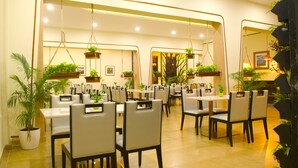 A restaurant with multiple tables and chairs, hanging plants, and a modern interior design. - Rangers Hotel (Devikolam)