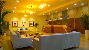 A modern lobby with a sofa, coffee table, and potted plants. - Rangers Hotel (Devikolam)