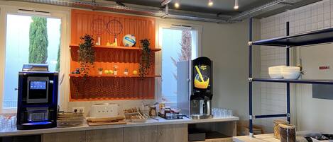 Une cuisine moderne dotée d’un plan de travail en bois, d’une machine à café et d’un distributeur de jus.