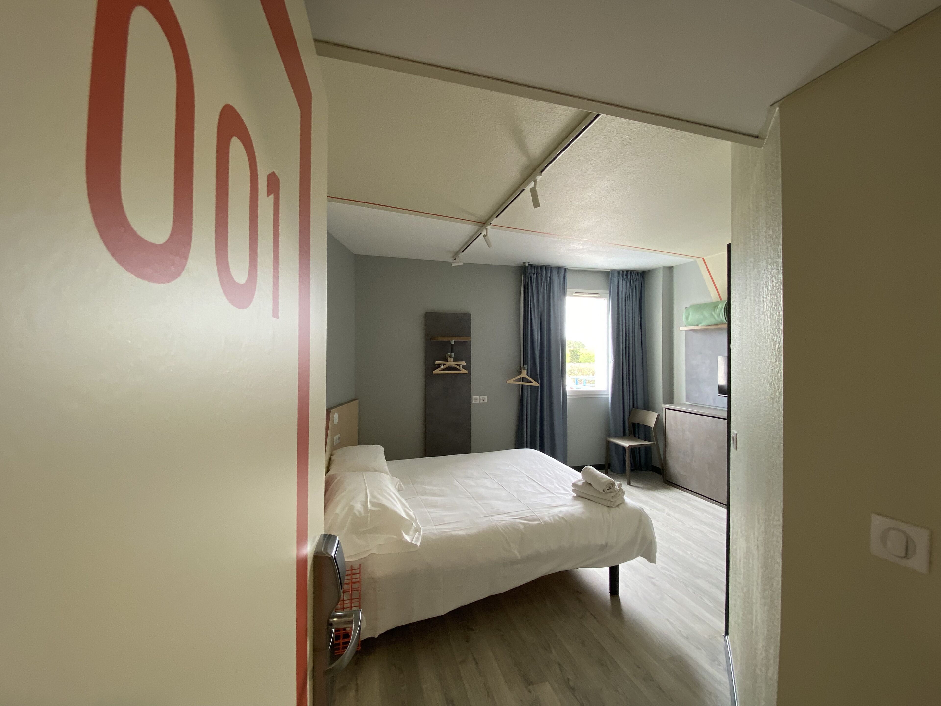Una habitación de hotel con cama, escritorio, silla y armario.