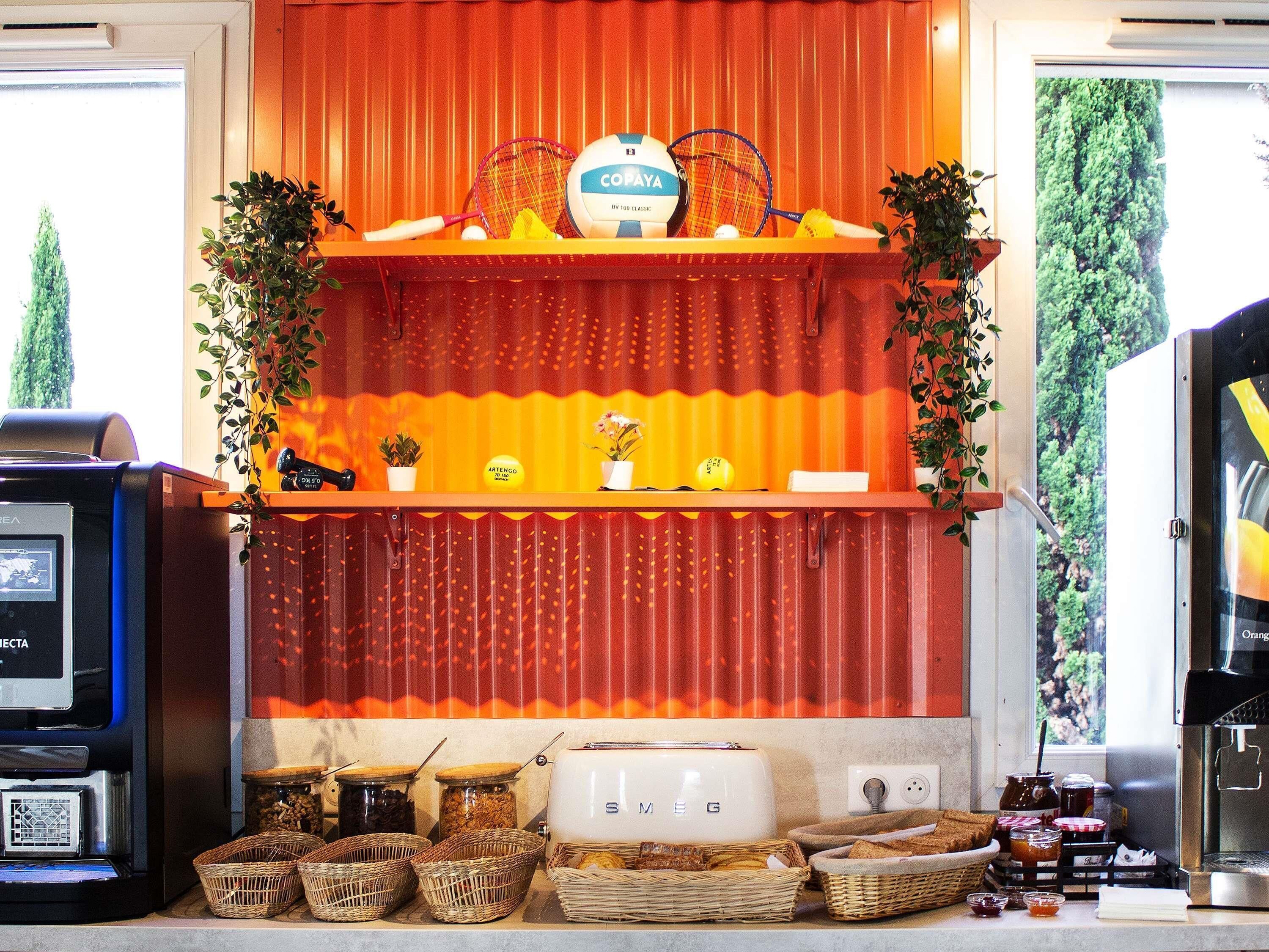 A kitchen area with a toaster, a coffee machine, and various food items on the counter.