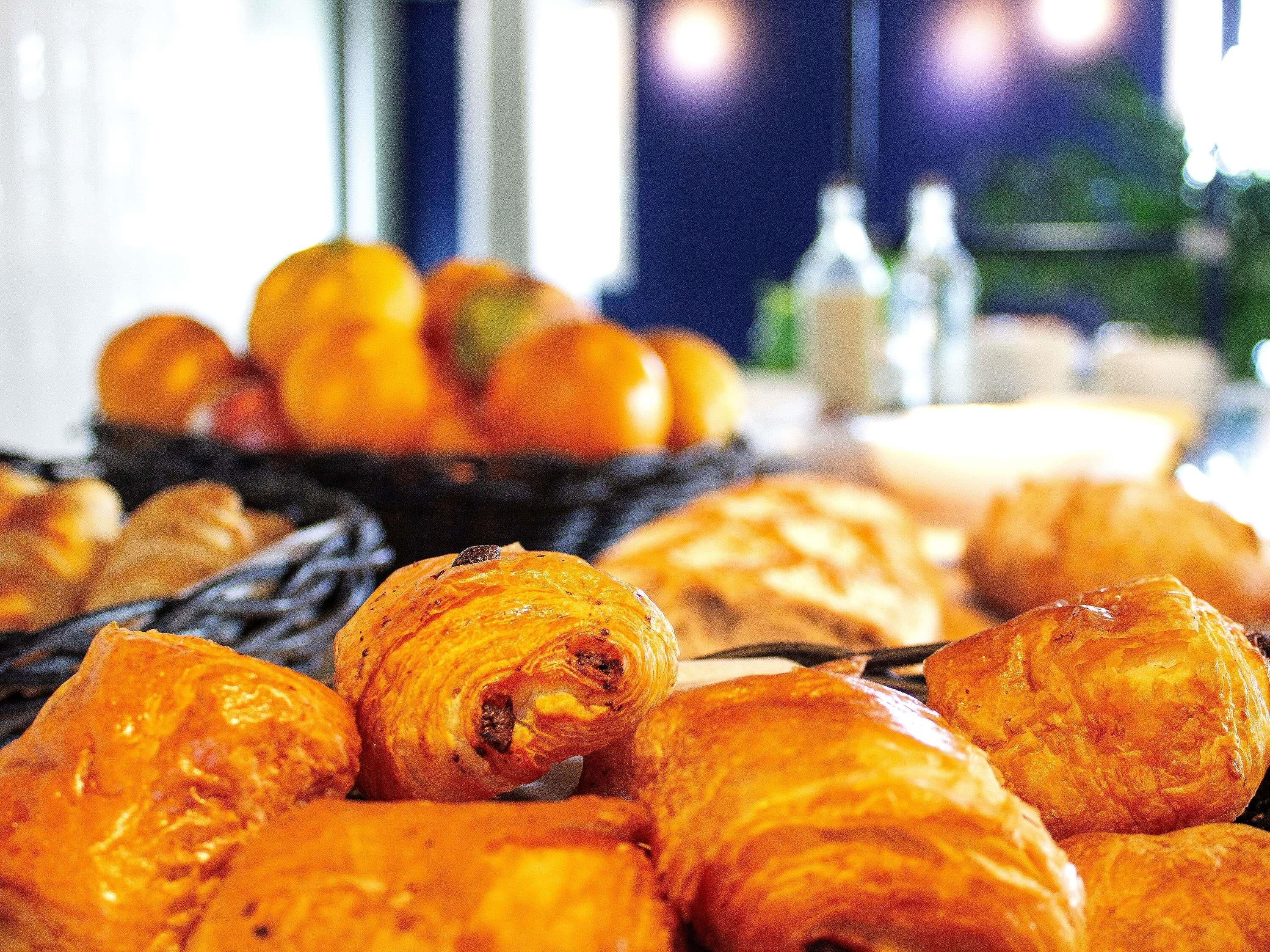A selection of pastries and fruits on a table, with a blurred background suggesting a dining area.
