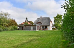 A house with a large lawn, a garage, and a dining area with outdoor furniture.