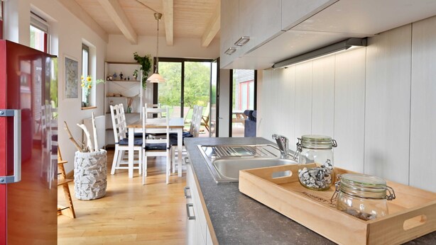 Een moderne keuken met een houten aanrecht, een spoelbak en een eethoek met witte stoelen en een tafel.