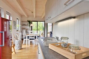 A modern kitchen with a wooden countertop, a sink, and a dining area with white chairs and a table.