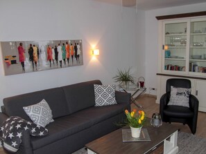 Un salon moderne avec un canapé, un fauteuil, une table basse et un tableau accroché au mur.