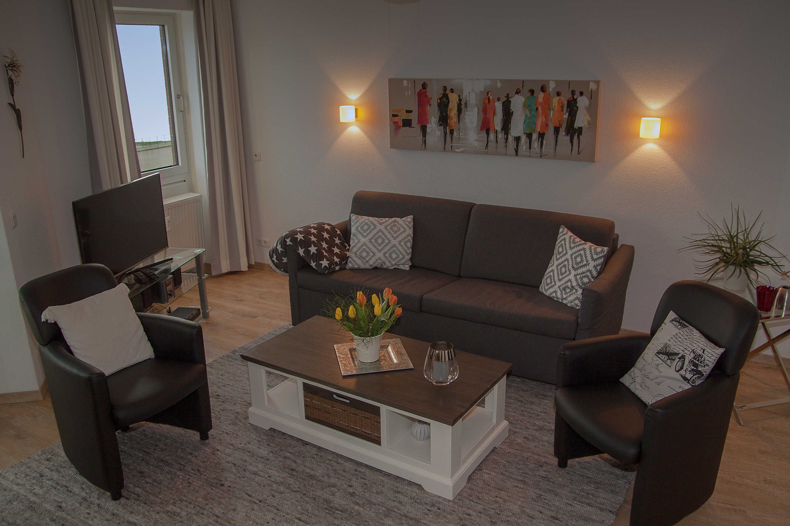 A living room with a sofa, two armchairs, a coffee table with a vase of flowers, and a painting on the wall.