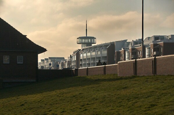 A building with a prominent tower, a brick wall, and a grassy area.