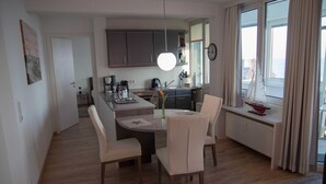 Una cocina moderna con armarios oscuros, una isla central y un comedor con sillas.