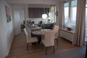 Una cocina moderna con armarios oscuros, una isla central y un comedor con sillas.