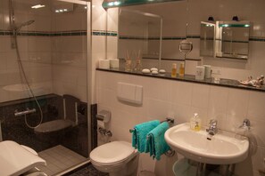 Un baño con ducha, inodoro, lavamanos y espejo.