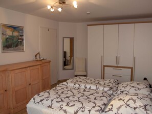 Un dormitorio con cama, armario de madera y espejo.