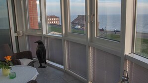 Una habitación con vistas al mar, una escultura de un pájaro negro y una mesa con un jarrón y una vela.