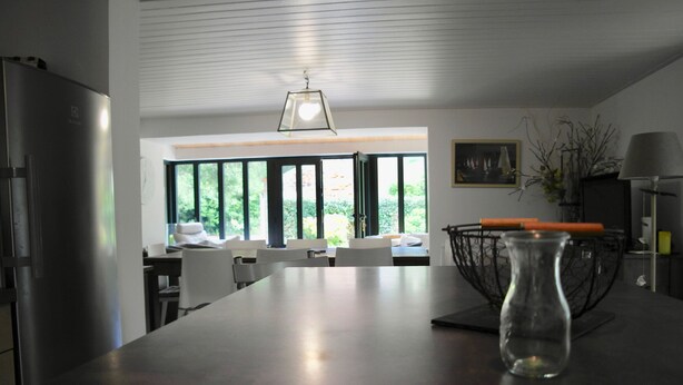 A modern kitchen with a large island, a refrigerator, and a dining area with a view through large windows. - 700m from Plage des Dames - House for 9 (Noirmoutier-en-l´Ile)