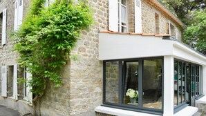 A stone building with a modern glass window and a tree growing against the wall. - 700m from Plage des Dames - House for 9 (Noirmoutier-en-l´Ile)