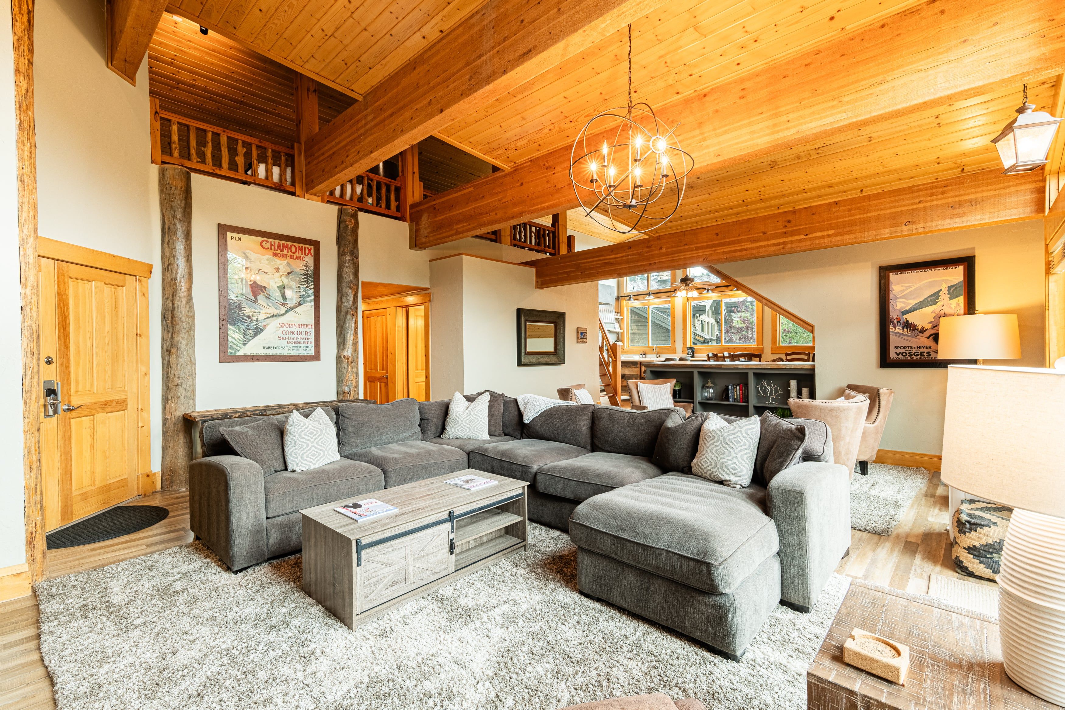 A spacious living area with a large sectional sofa, a wooden ceiling, and a chandelier.