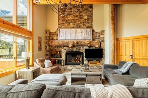 A cozy living room with a stone fireplace, a television, and comfortable seating.