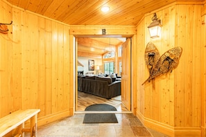 A wooden interior with a bench, a door leading to a living area, and a wall-mounted light fixture.