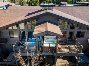 A two-story building with a balcony, large windows, and a hot tub. - Private Hot tub & BBQ, Shuttle! Luxury Amenities & walk to lifts (Park City)