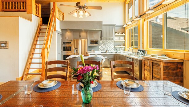 A dining area with a wooden table, chairs, and a vase of flowers. - Private Hot tub & BBQ, Shuttle! Luxury Amenities & walk to lifts (Park City)