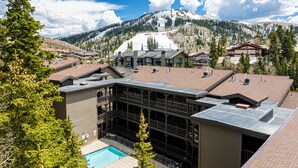 A hotel with a pool, multiple floors, and a view of snow-capped mountains. - Private Hot tub & BBQ, Shuttle! Luxury Amenities & walk to lifts (Park City)