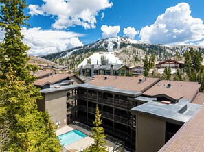 A hotel with a pool, multiple floors, and a view of snow-capped mountains. - Private Hot tub & BBQ, Shuttle! Luxury Amenities & walk to lifts (Park City)