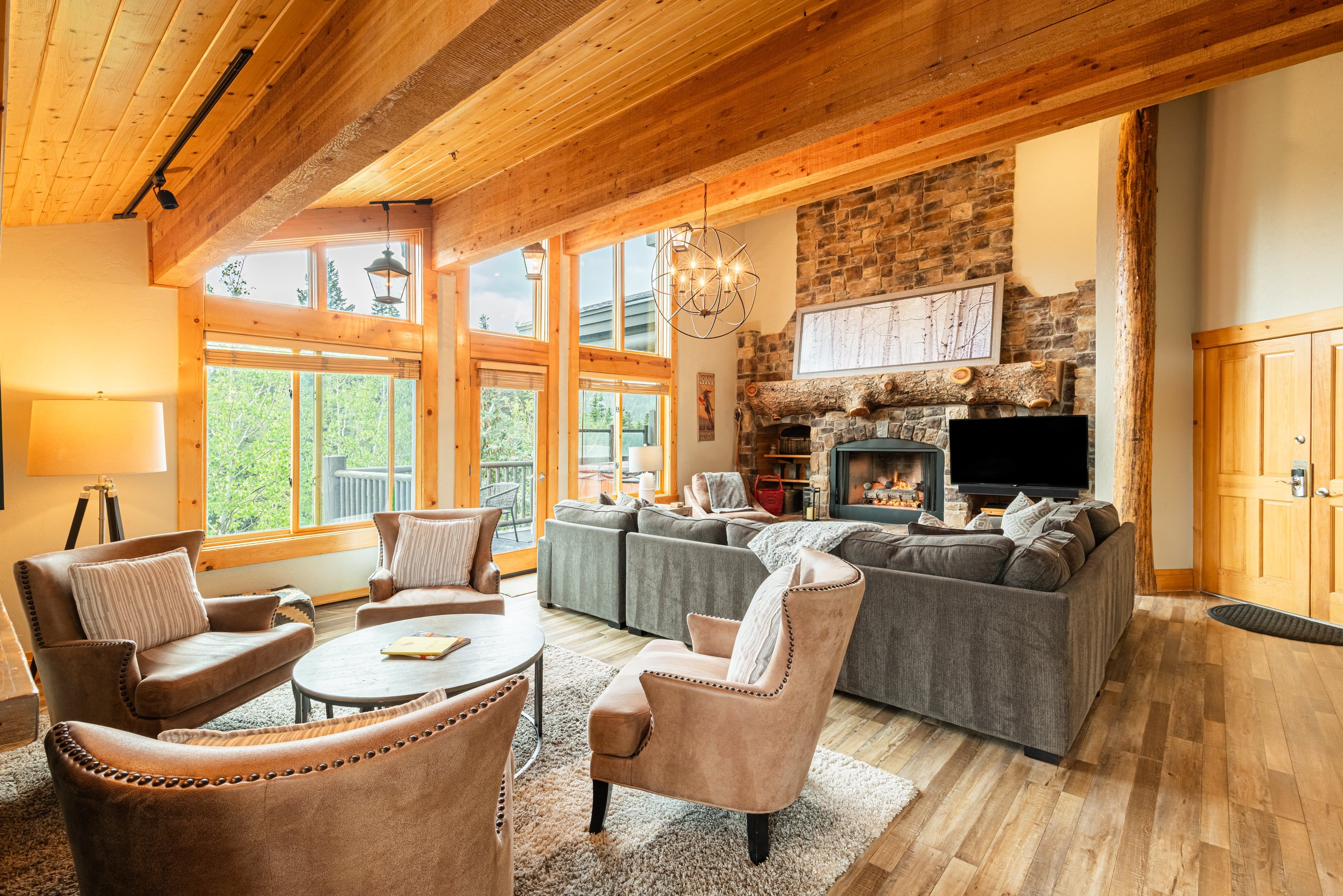 A spacious living room with a stone fireplace, large windows, and a cozy seating area.