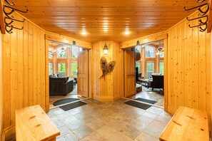 Un intérieur en bois avec une porte centrale, deux portes latérales et un espace salon comprenant un canapé et des fauteuils.