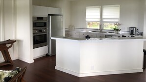 A modern kitchen with white cabinetry, a central island, and a built-in oven.