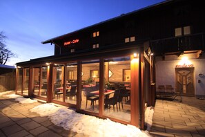 A hotel with a glass facade, outdoor seating, and a sign reading "Hotel - Cafe". - Hotel Cafe Hanfstingl (Egling)