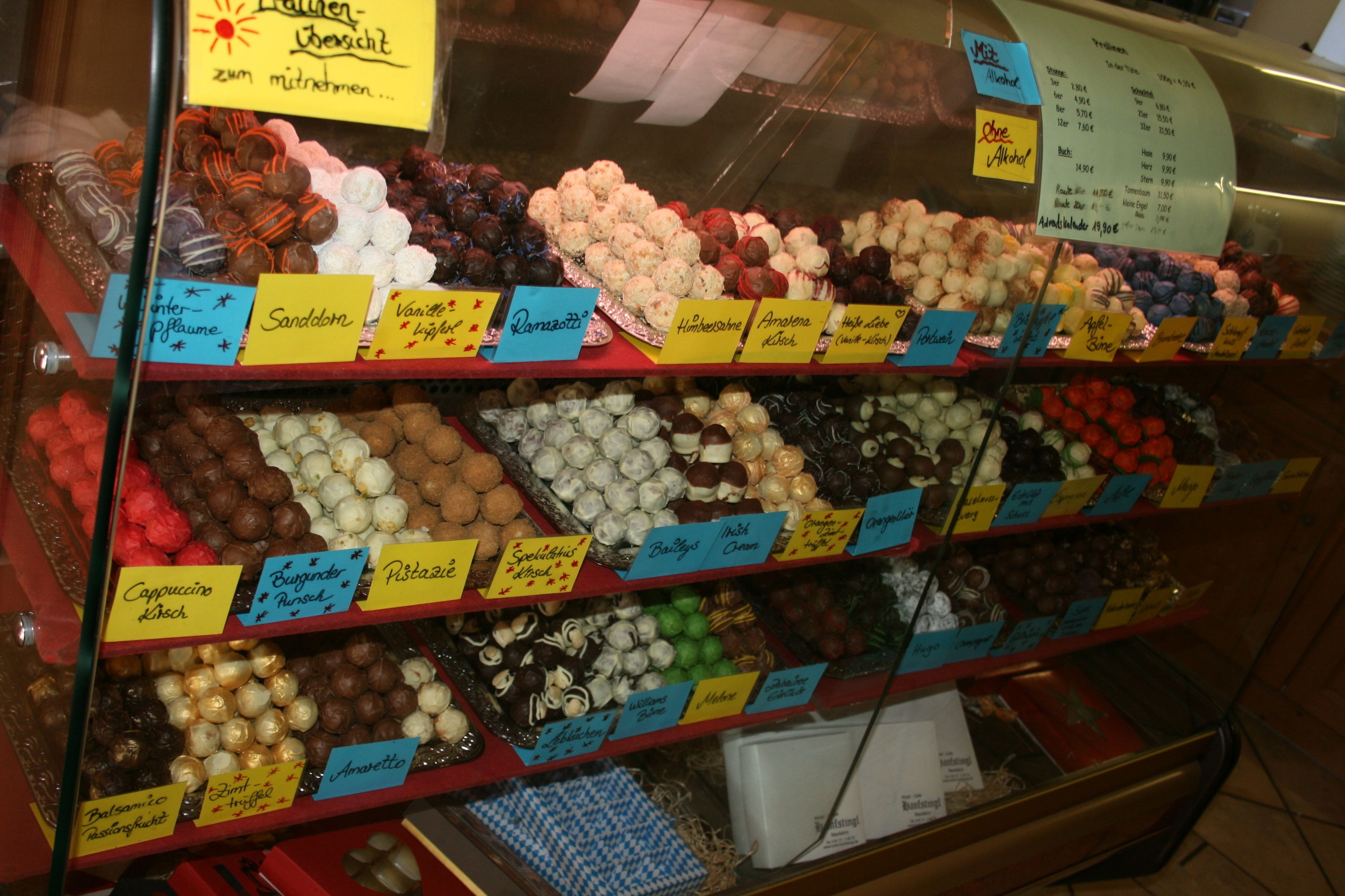 Eine Auslage mit verschiedenen Pralinen, mit Etiketten, die Namen und Preise angeben.