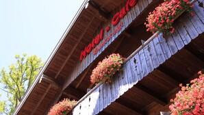 Un hotel con fachada de madera y balcones adornados con flores rojas.