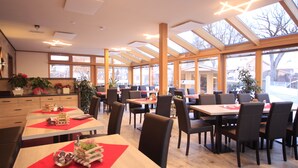 Un restaurante espacioso con techos altos, ventanas amplias y mobiliario moderno.