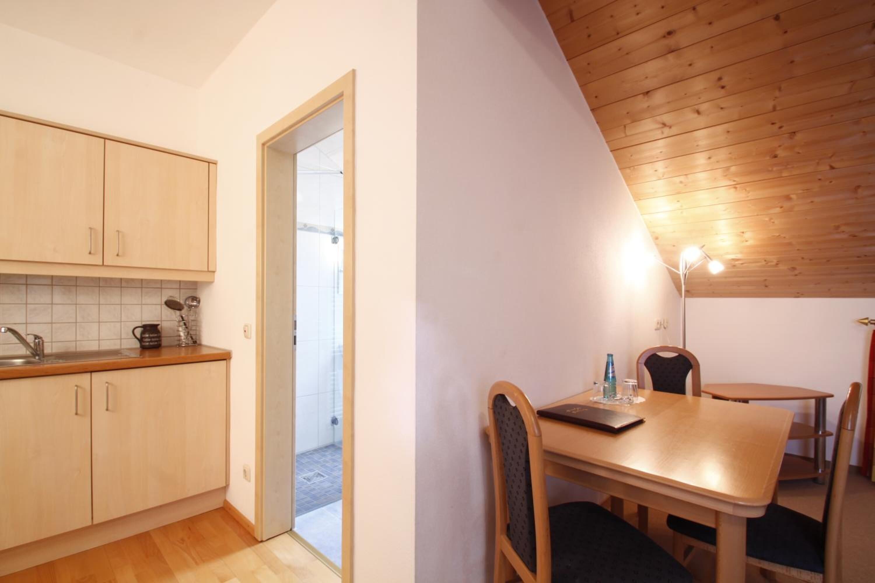 A compact kitchen with wooden cabinets and a dining area with a table and chairs.