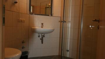 Une salle de bain équipée de toilettes, d’un lavabo et d’une douche à parois en verre.