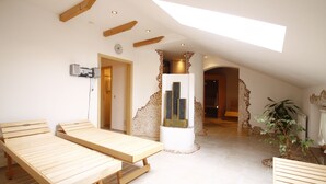 Una habitación con dos camas de madera, una pared de piedra, un pilar blanco y una planta.