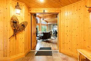 A wooden interior with a door leading to a living area featuring a couch, chairs, and a dining table.
