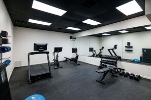 Un gimnasio con cintas de correr, bancos de pesas y mancuernas.