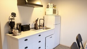 A compact kitchenette with a coffee maker, toaster, microwave, and refrigerator. - Harbour Inn guesthouse (Vesturbyggð)