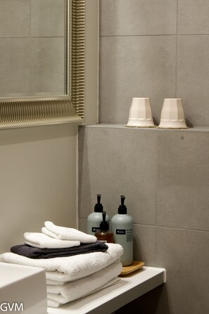 A bathroom with a stack of towels, two bottles of lotion, and a mirror. - Harbour Inn guesthouse (Vesturbyggð)